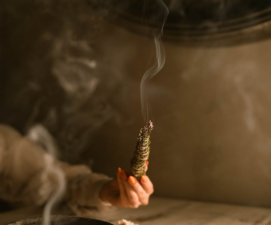 persona sosteniendo una hierba humeante